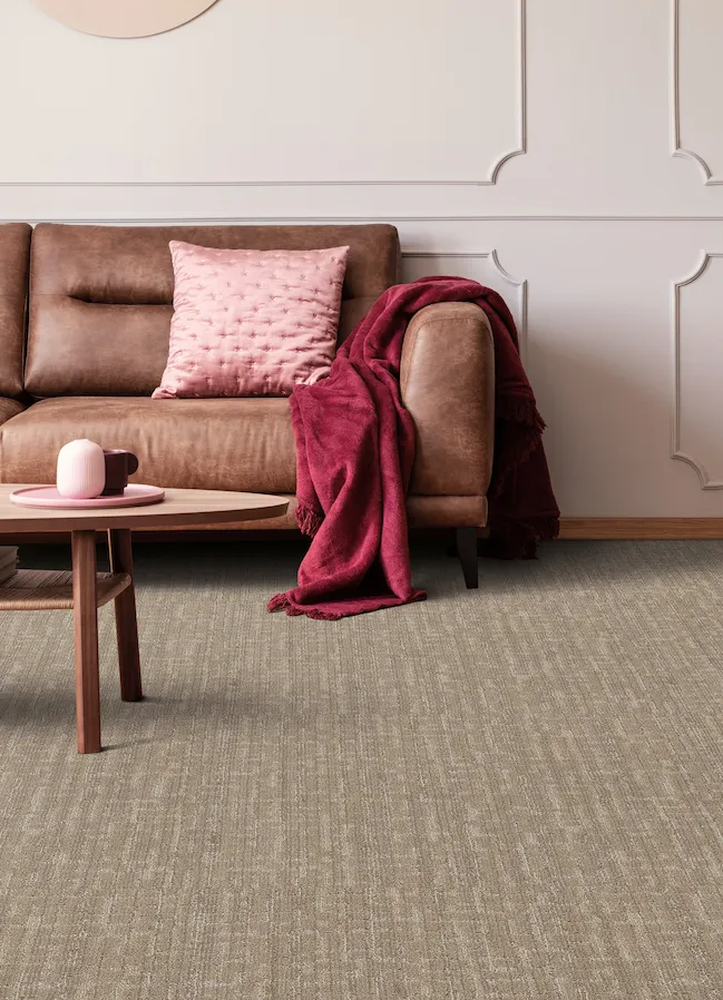 textured brown carpets in a living room with pink accents and brown leather couch