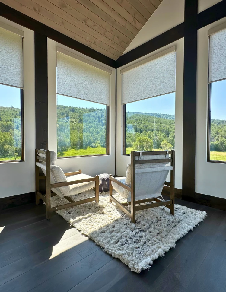 Window coverings over looking mountain with white chairs and white rug