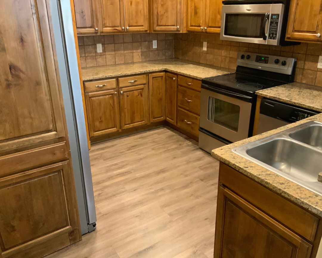 wood look flooring in kitchen with wood cabinets and tile backsplash